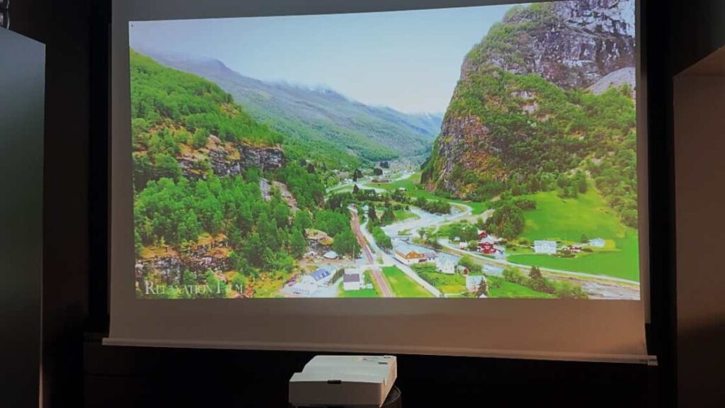 Ultra Short Throw Beamer projiziert auf eine Motorleinwand aus kurzer Distanz