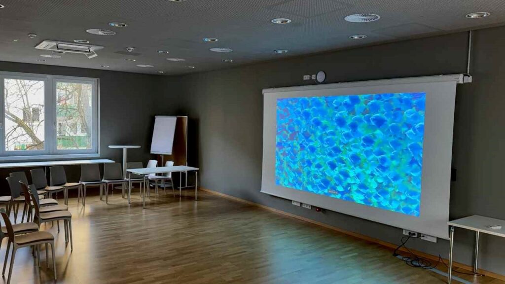 Weiße Motorleinwand mit Unterwasserwelt in einem dunklen Raum mit Stühlen