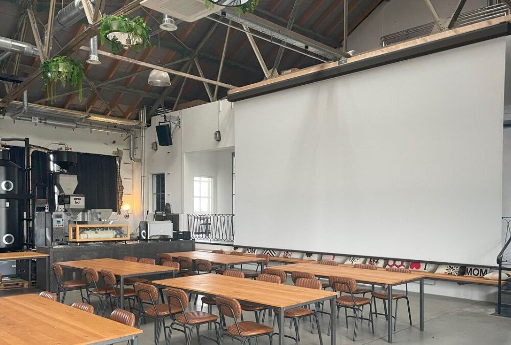 Großmotorleinwand von Stiers in einem modernen Veranstaltungsraum mit Loft-Charakter und Holzmobiliar.