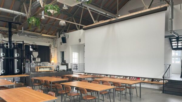 Großmotorleinwand von Stiers in einem modernen Veranstaltungsraum mit Loft-Charakter und Holzmobiliar.